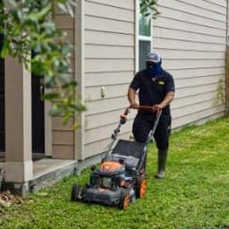 During: crew member mowing the lawn beside a house