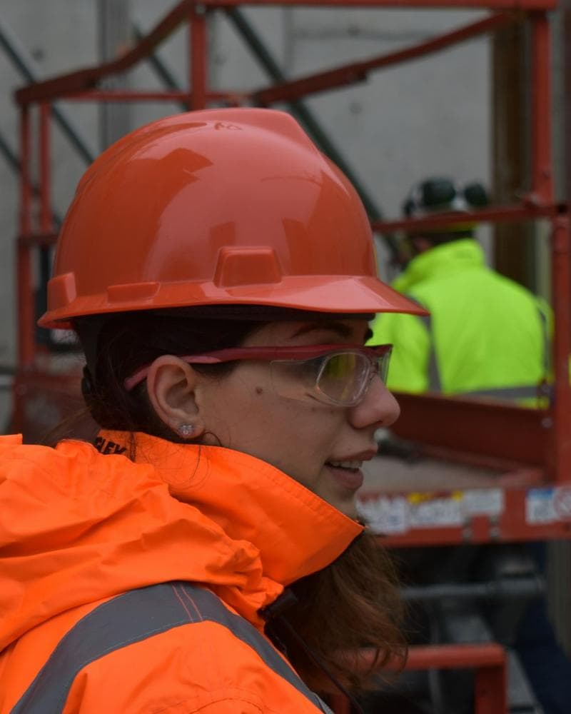 Field technician in a hard hat and high-visibility jacket on a job site